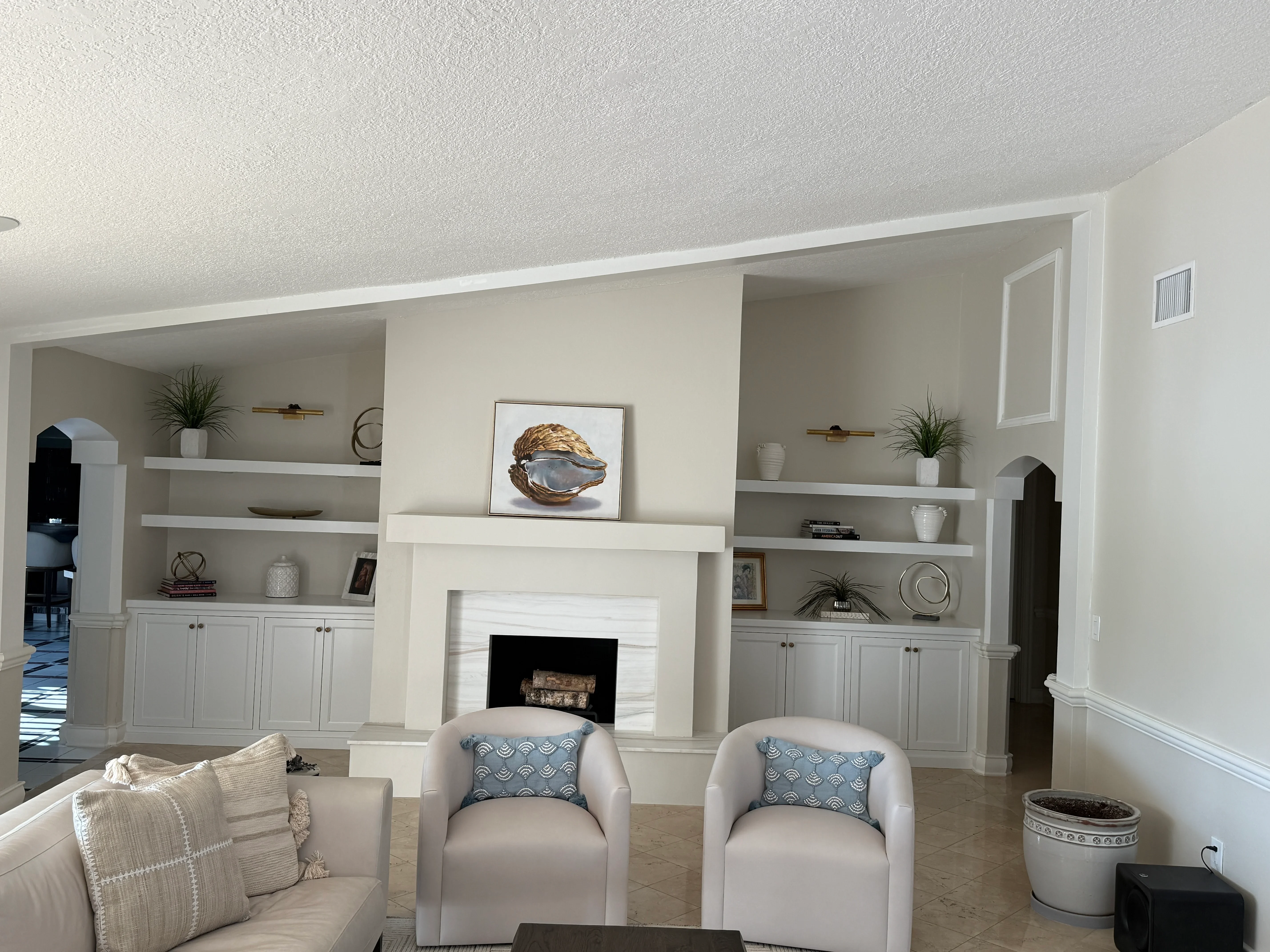 White fireplace surround with built-in shelving, brass accents, and decorative items