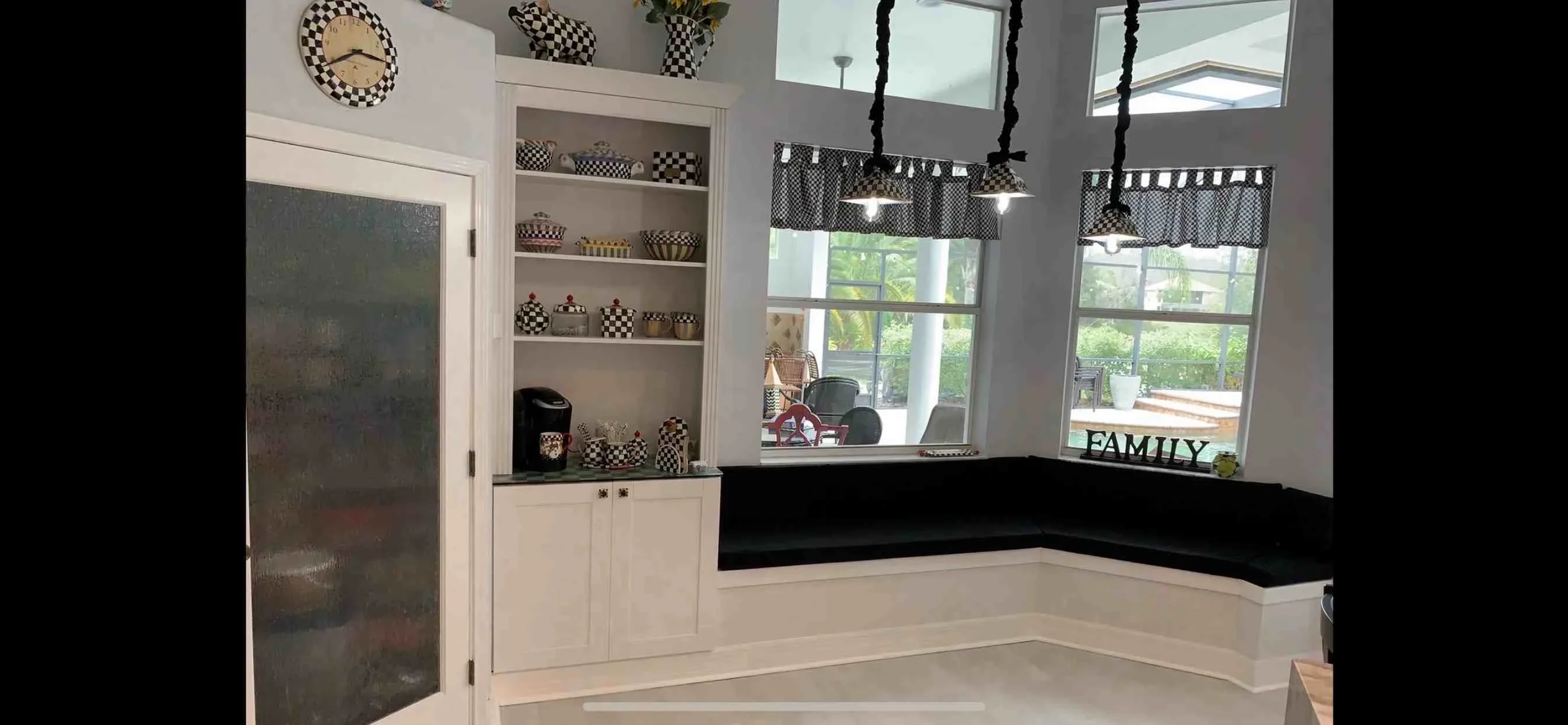 Modern kitchen with white cabinets, black countertop, open shelving, and pendant lights