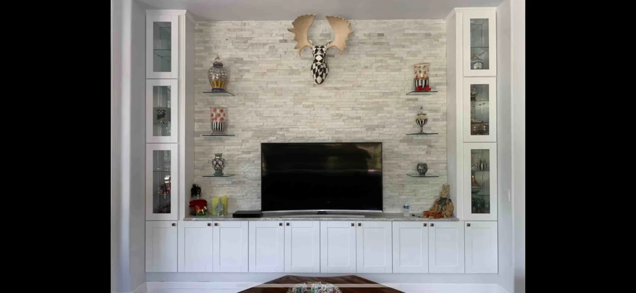 White built-in entertainment center with brick accent wall and display shelving