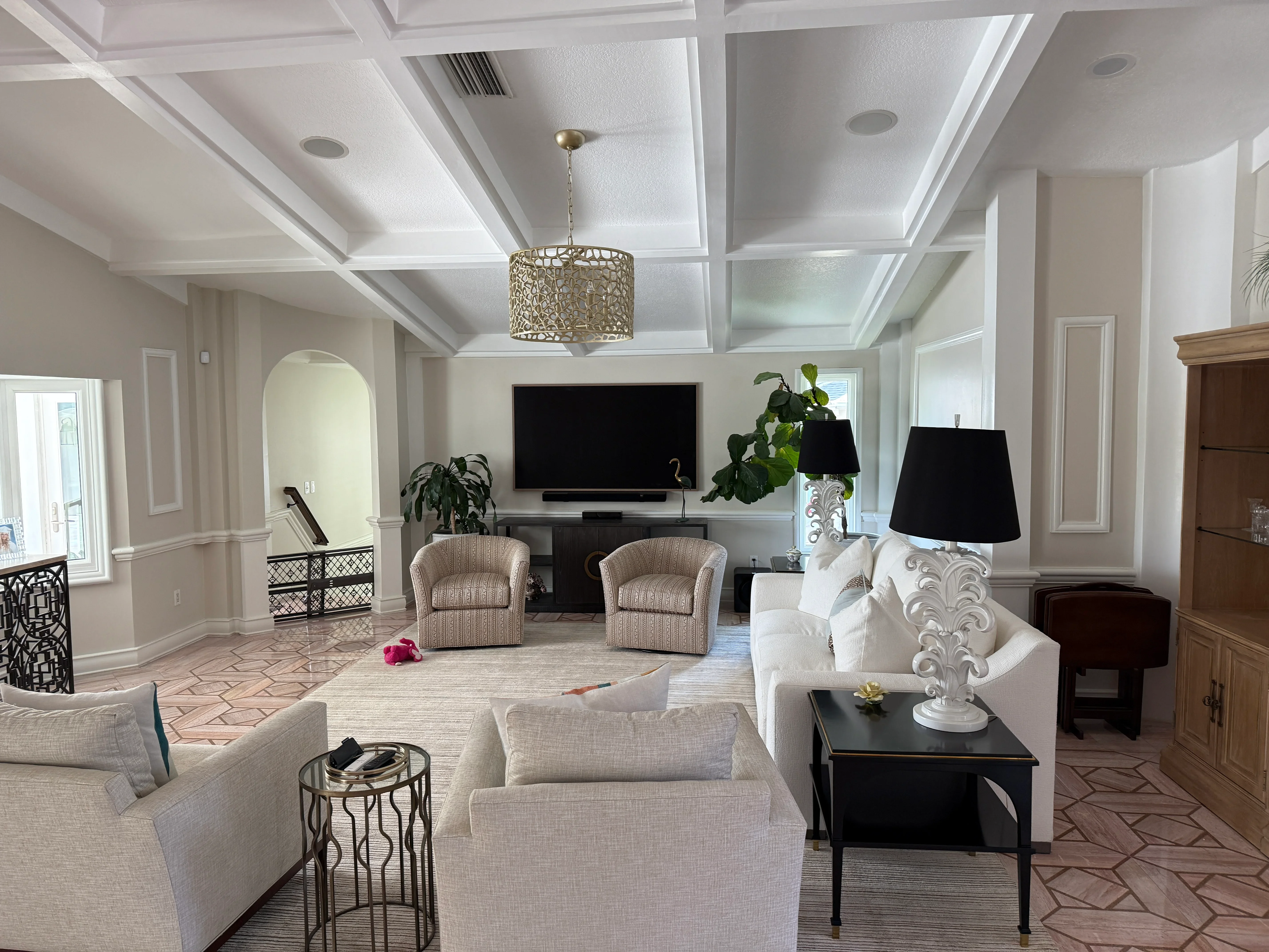 Elegant living room with coffered ceiling, neutral furnishings, and built-in entertainment center