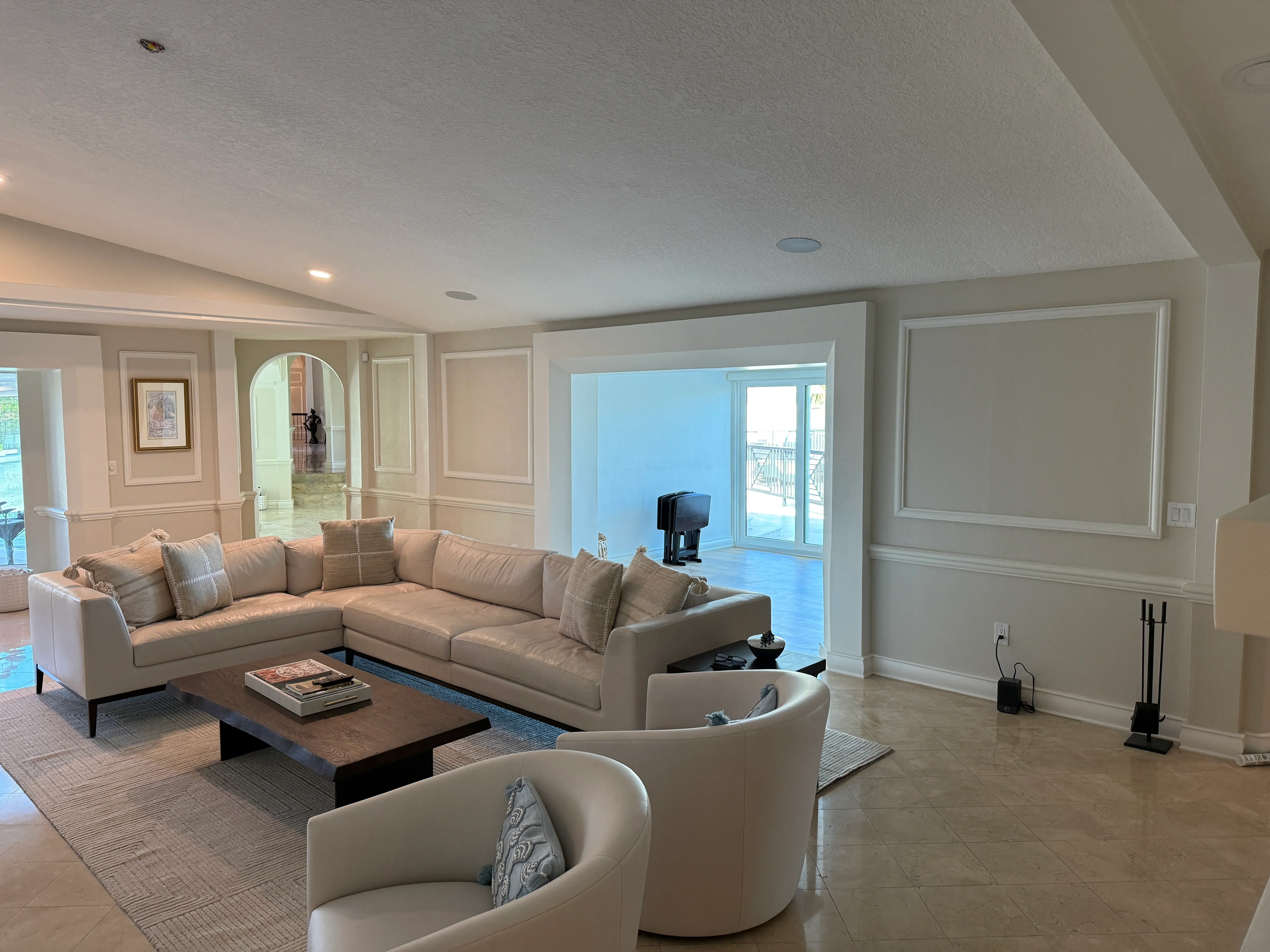 Luxury living room with cream sectional sofa, custom wall paneling, and glass doors