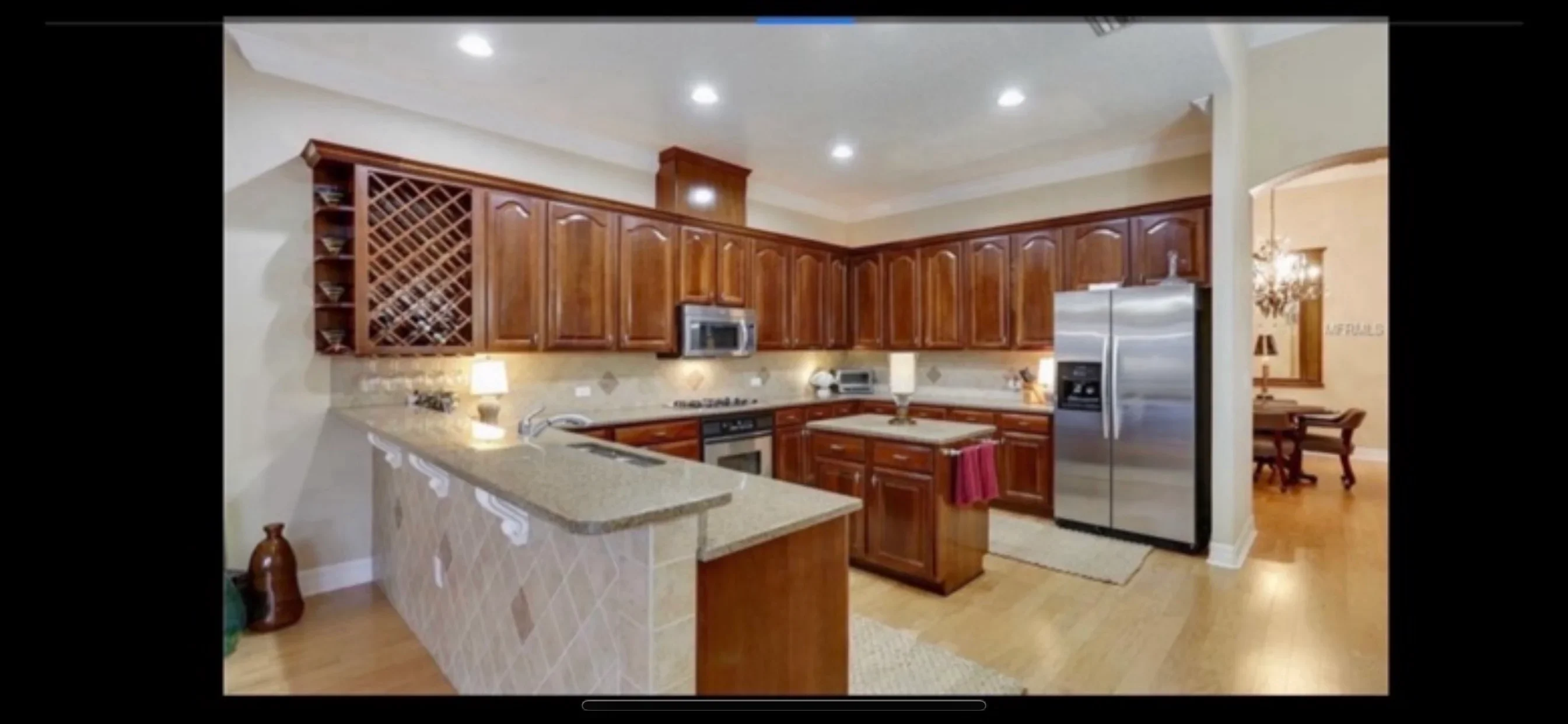 Modern kitchen with cherry cabinets, quartz counters, stainless steel appliances, and island