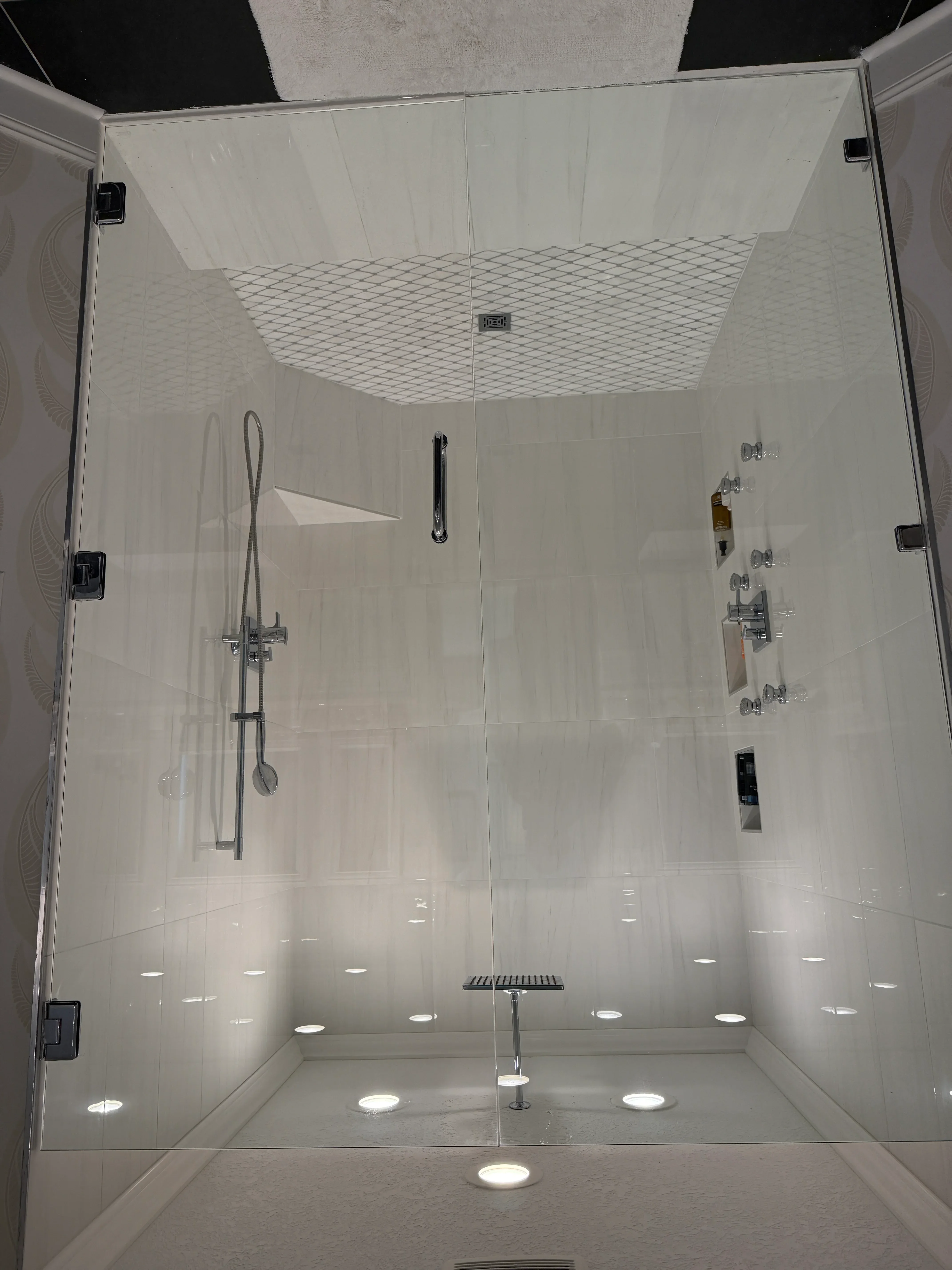 Modern frameless glass shower with white subway tile, chrome fixtures, and diamond accent tile