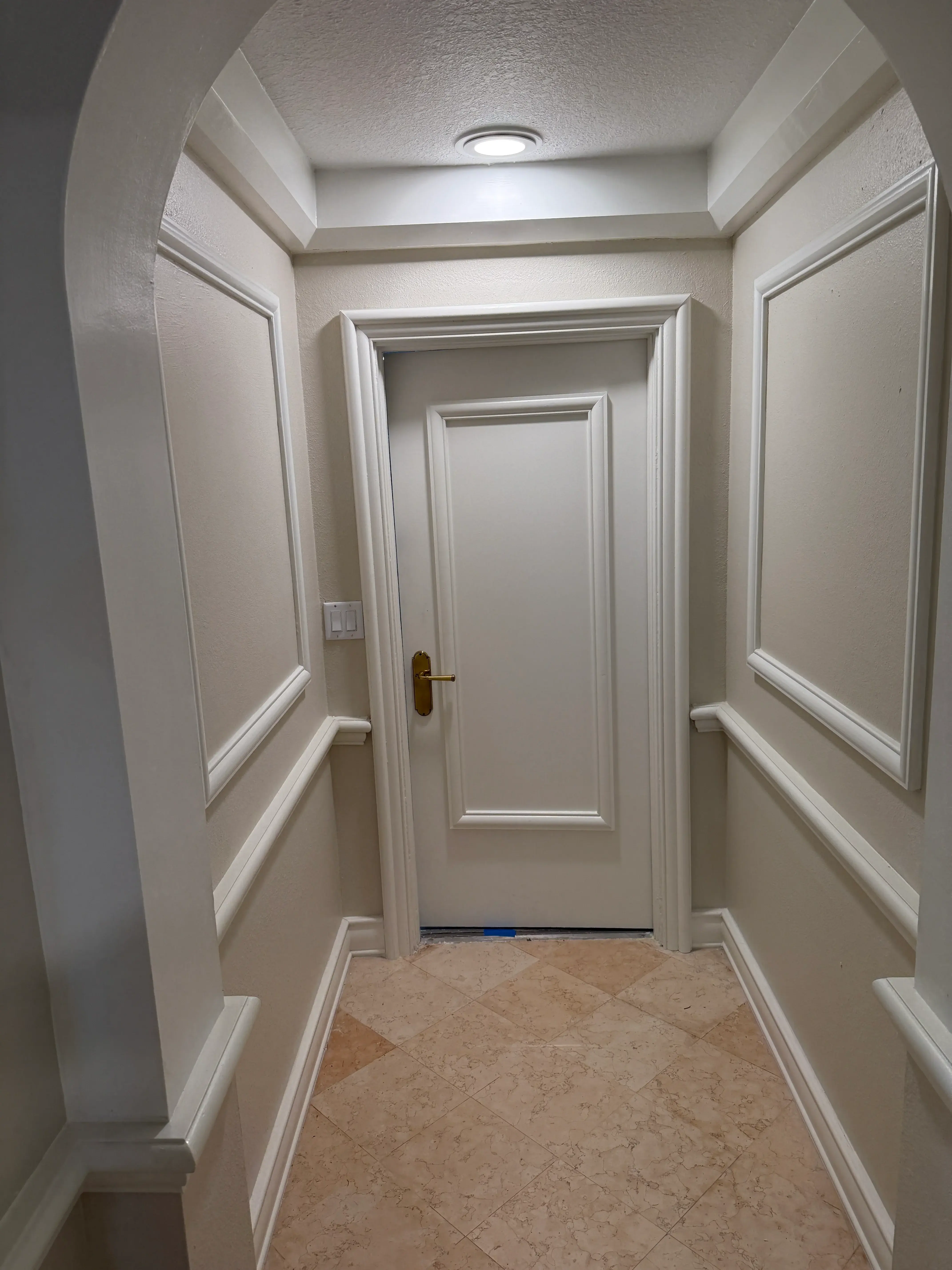 Bathroom with white millwork, coffered ceiling, and travertine tile accent wall