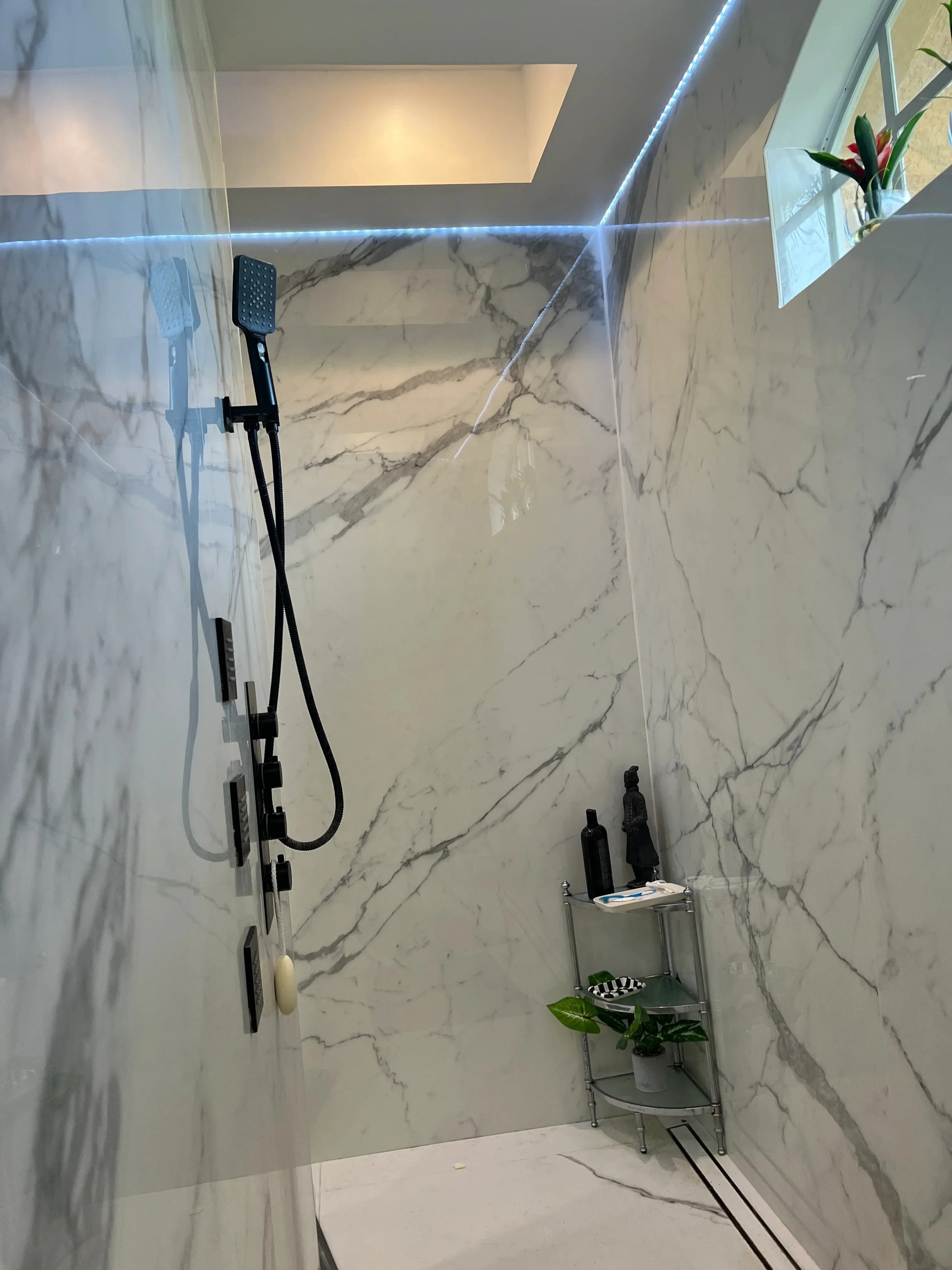 Modern bathroom shower with marble-look tile, glass enclosure, and black fixtures