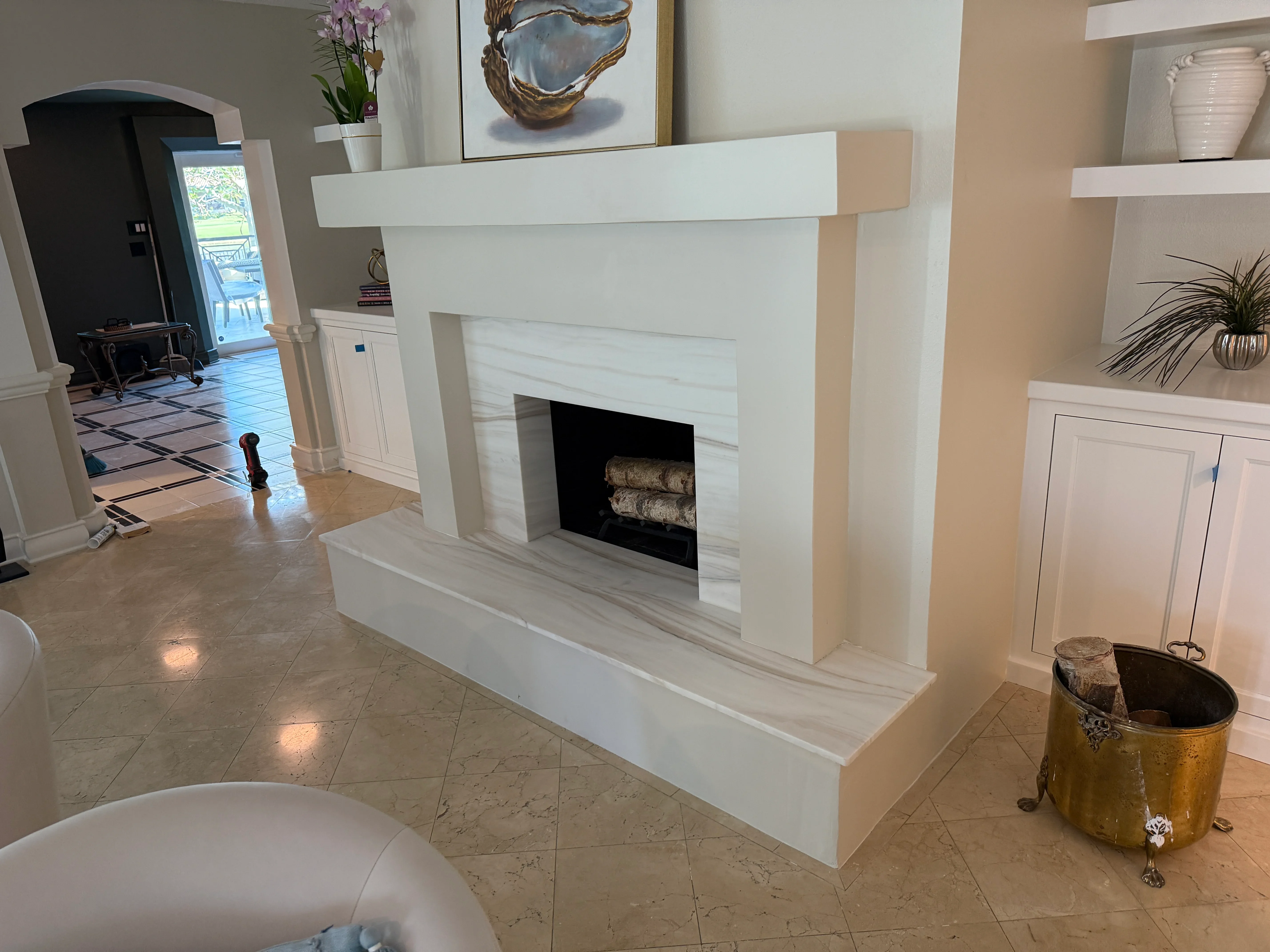 White modern fireplace surround with black firebox opening and decorative logs