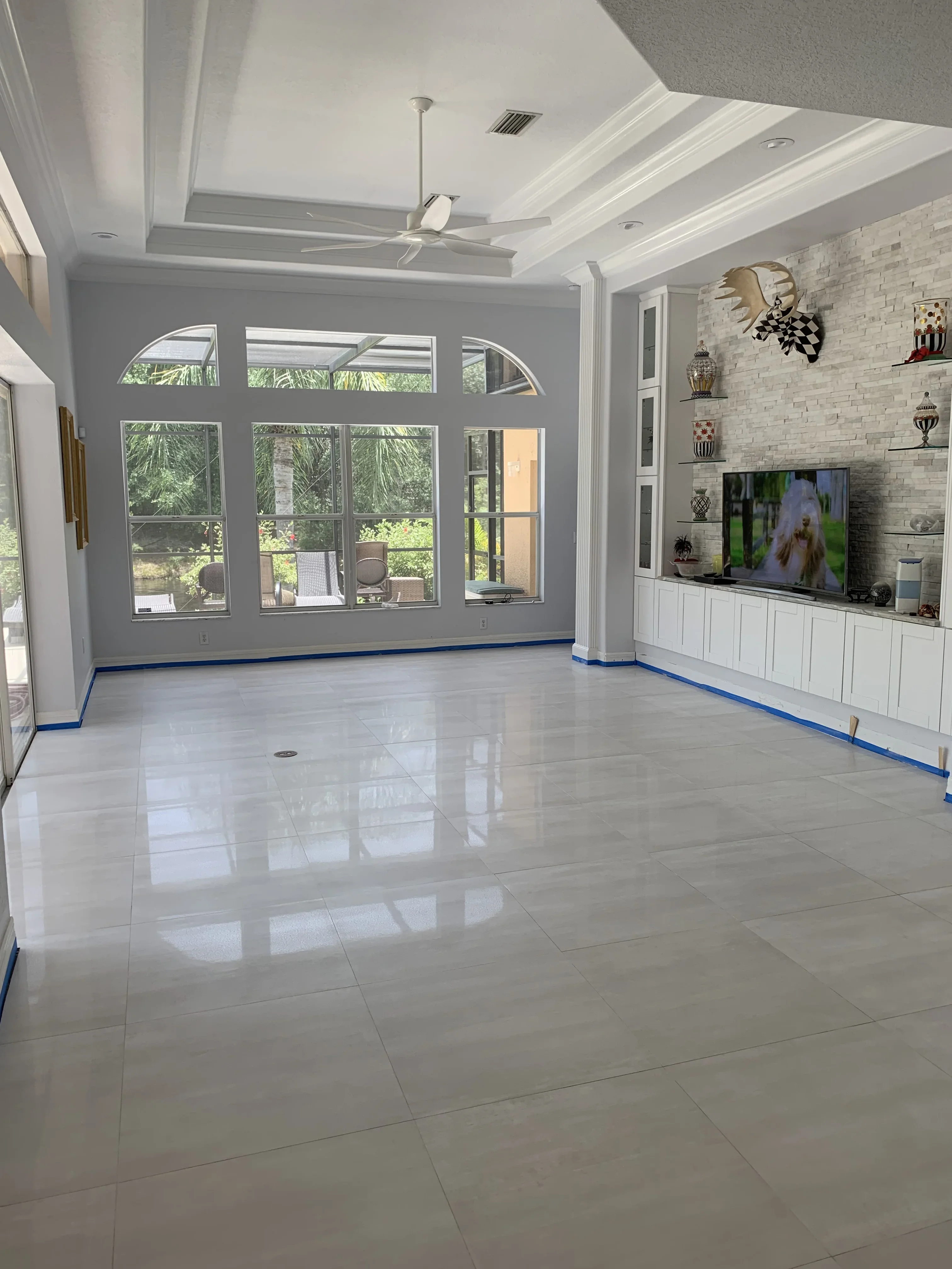 Bright great room with coffered ceiling, glass doors, and white built-in entertainment center