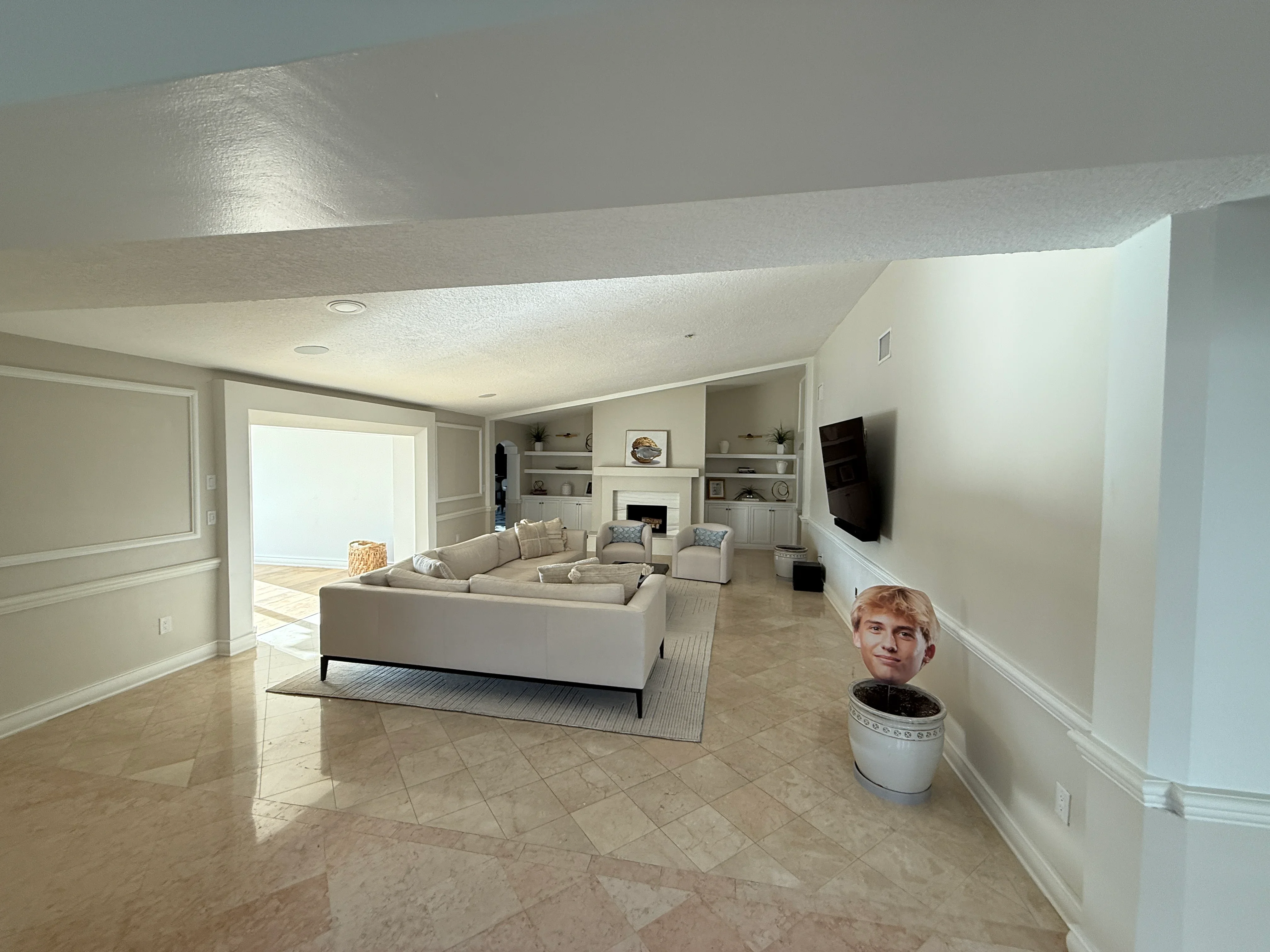 Finished basement with cream sectional sofa, custom built-in shelving, fireplace, and polished concrete floors