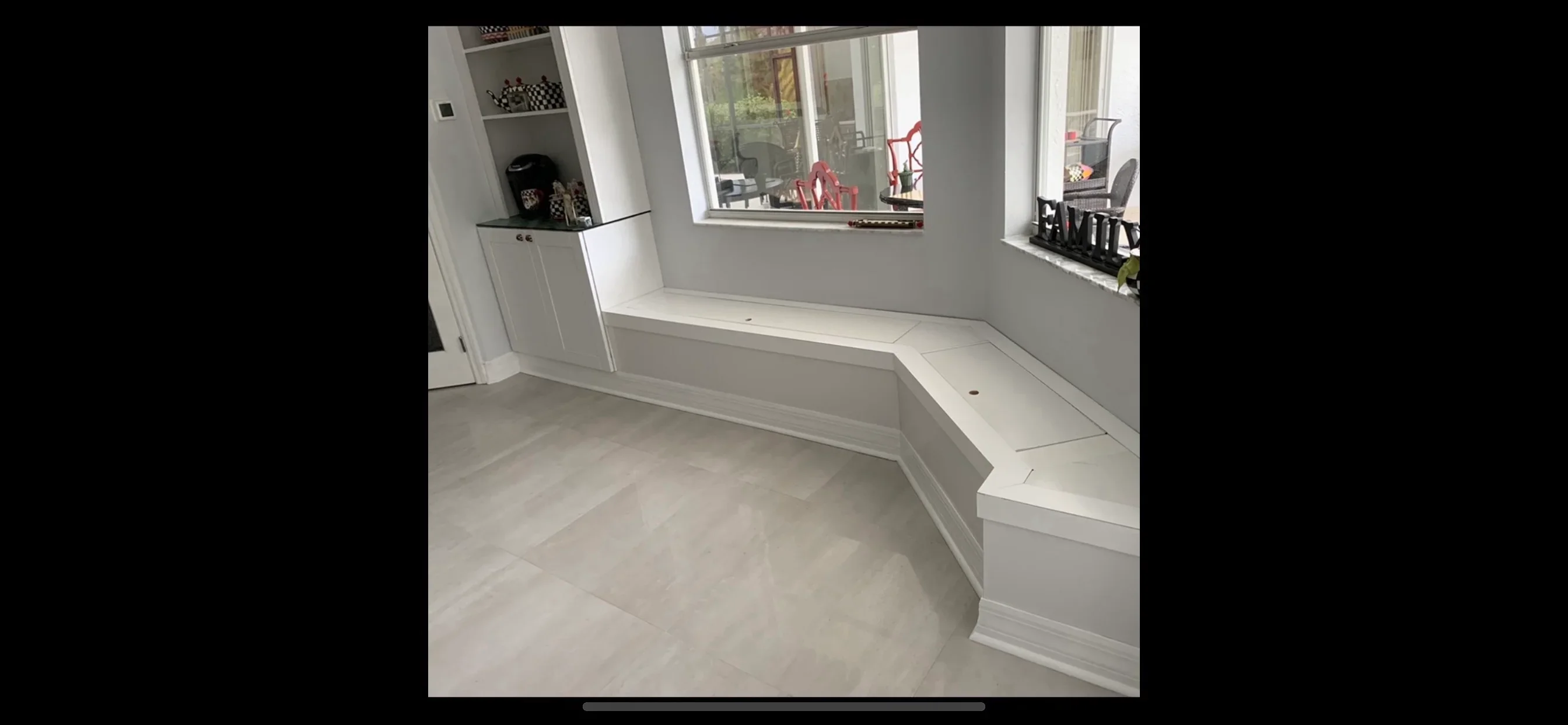 Bright bathroom with herringbone tile floor, white cabinetry, and built-in window bench