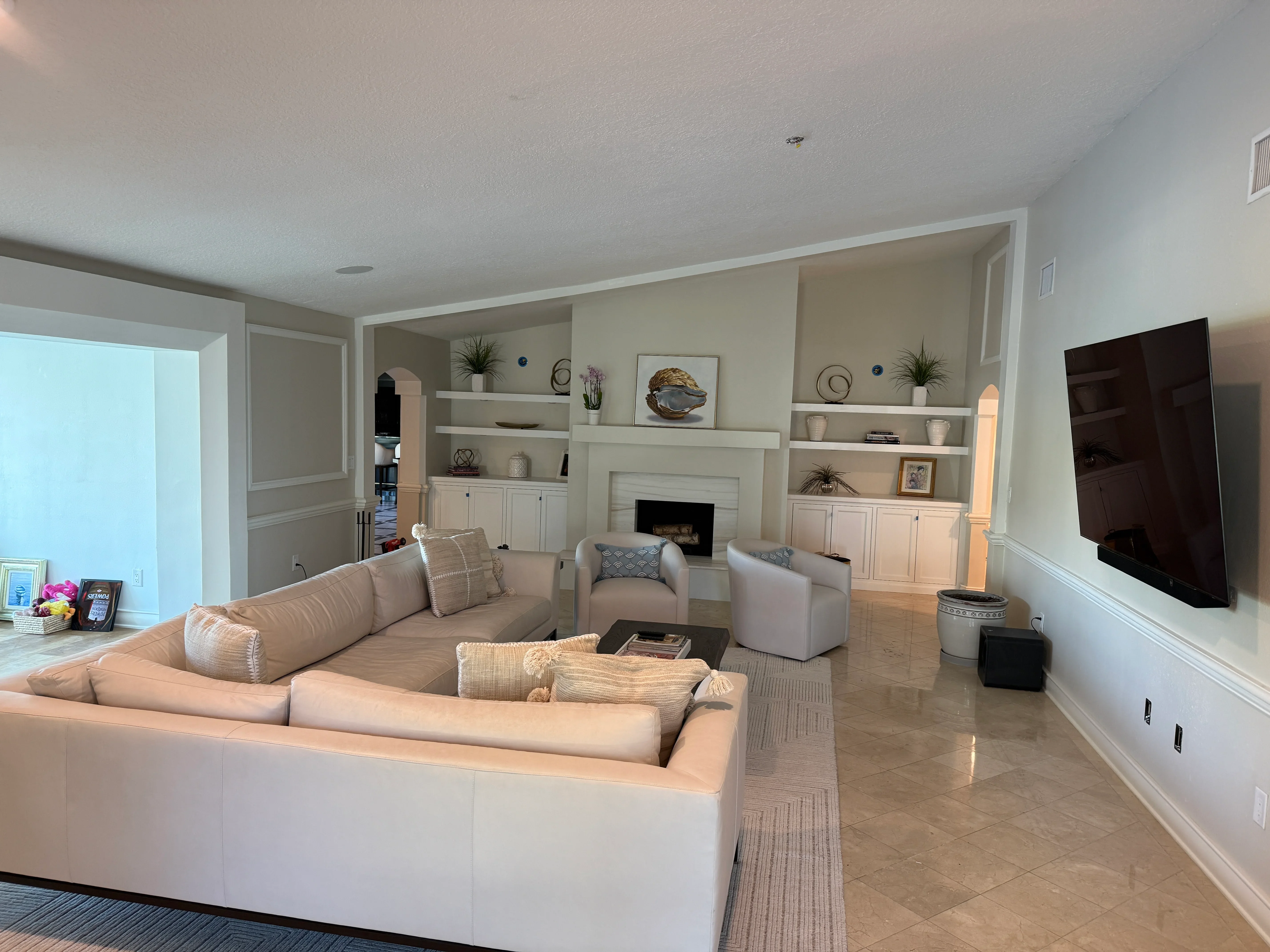 Modern living room with white built-in cabinetry, fireplace, and neutral furnishings