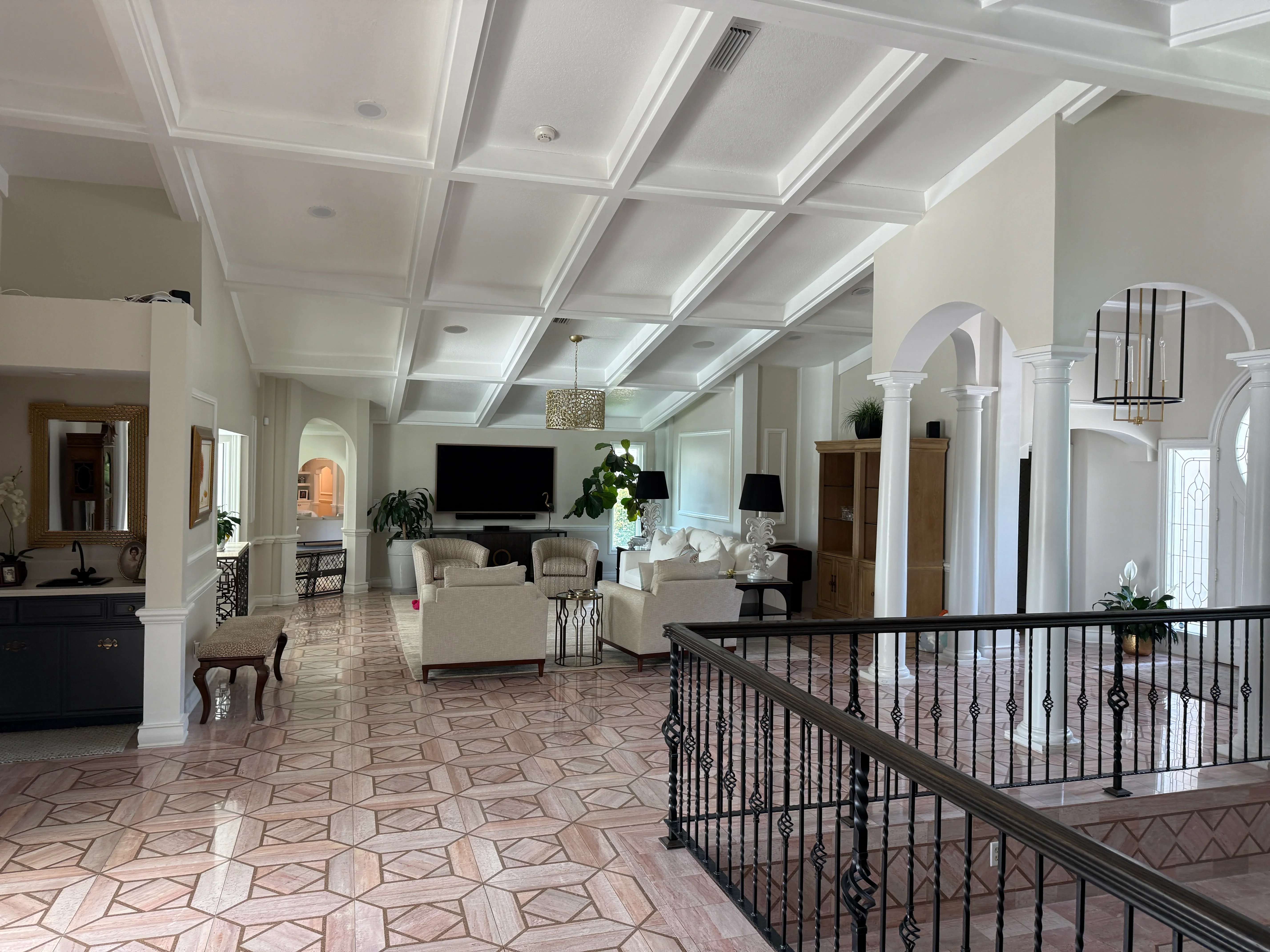 Luxury living room with coffered ceiling, columns, and geometric wood flooring